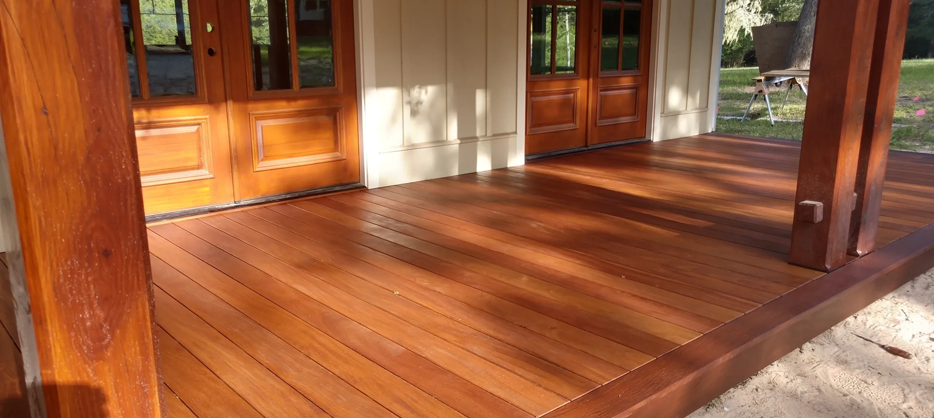 Wooden porch with doors and sunlight.