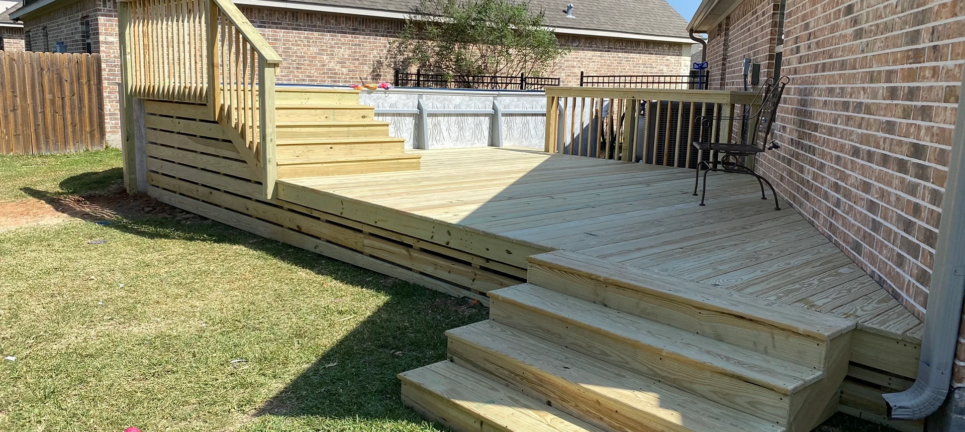 Wooden deck with stairs and chair.