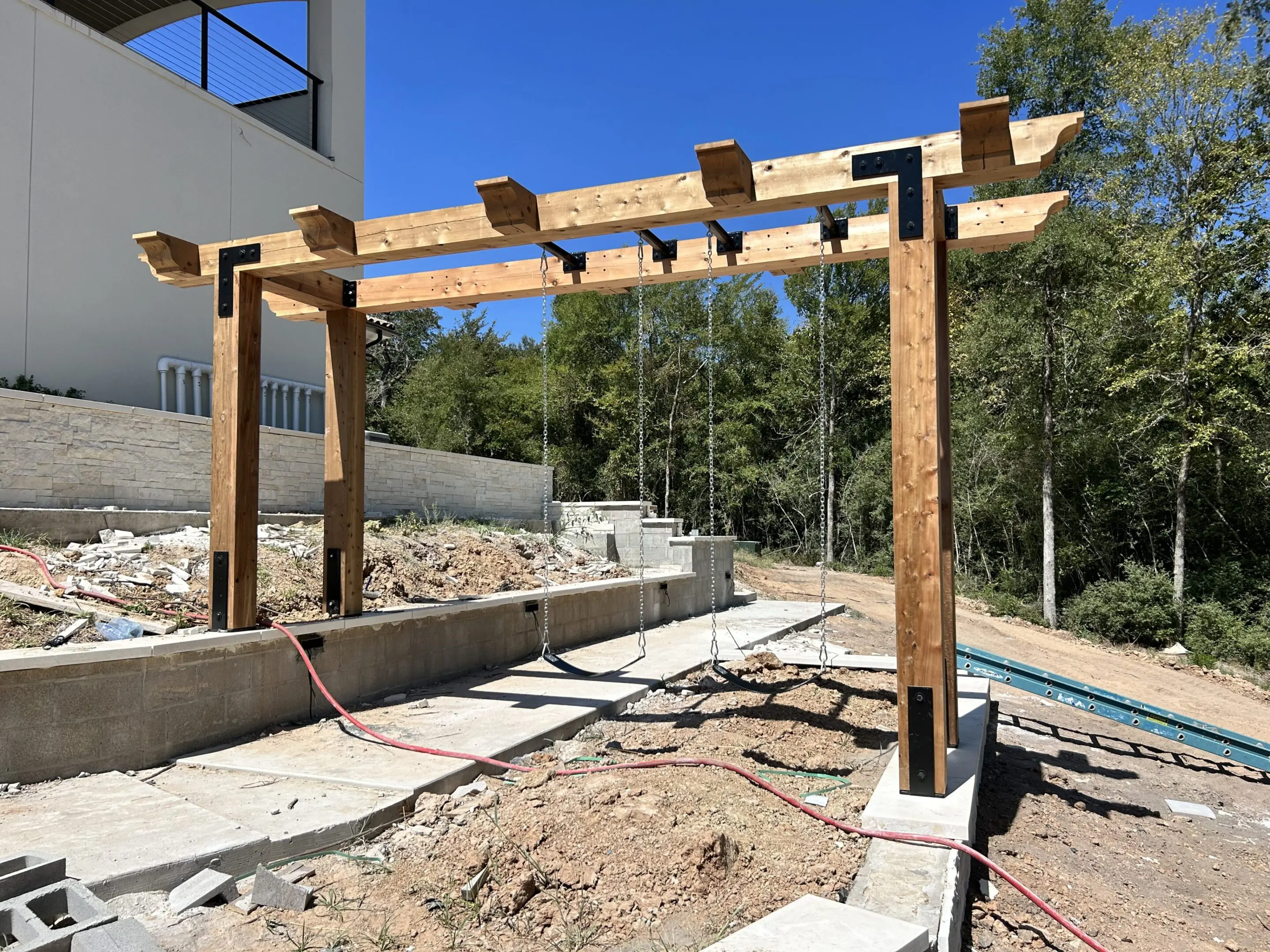 Wooden pergola under construction in a sunny backyard.