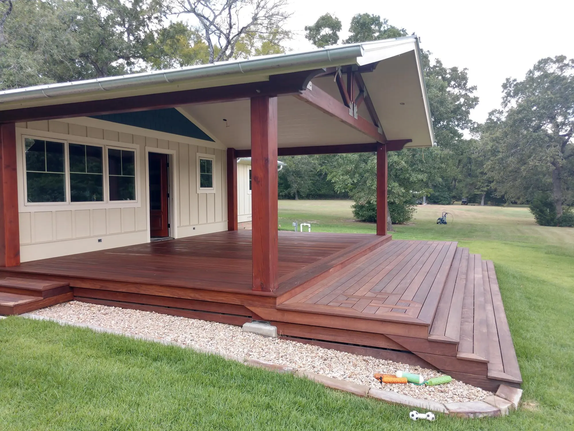 A spacious wooden deck with steps attached to a house surrounded by grass.