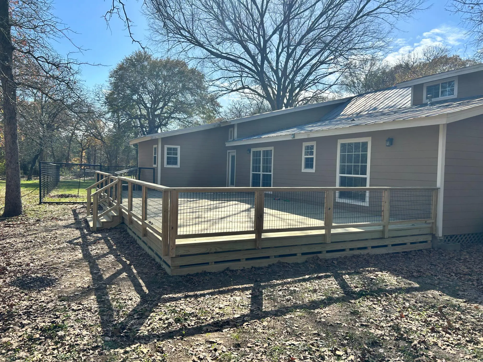 Newly built wooden deck with railings attached to a house.