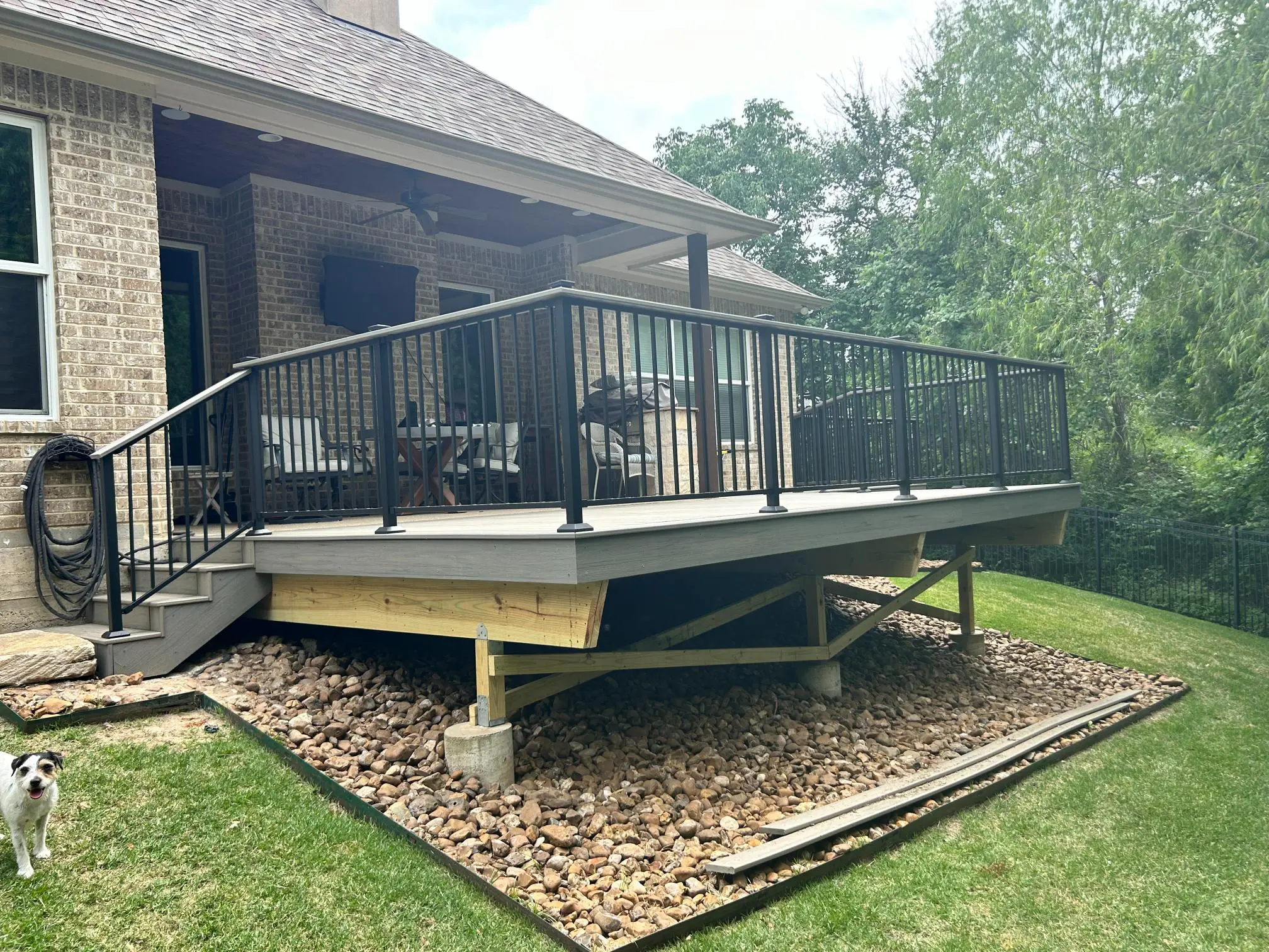A newly constructed elevated deck with black railing attached to a house.