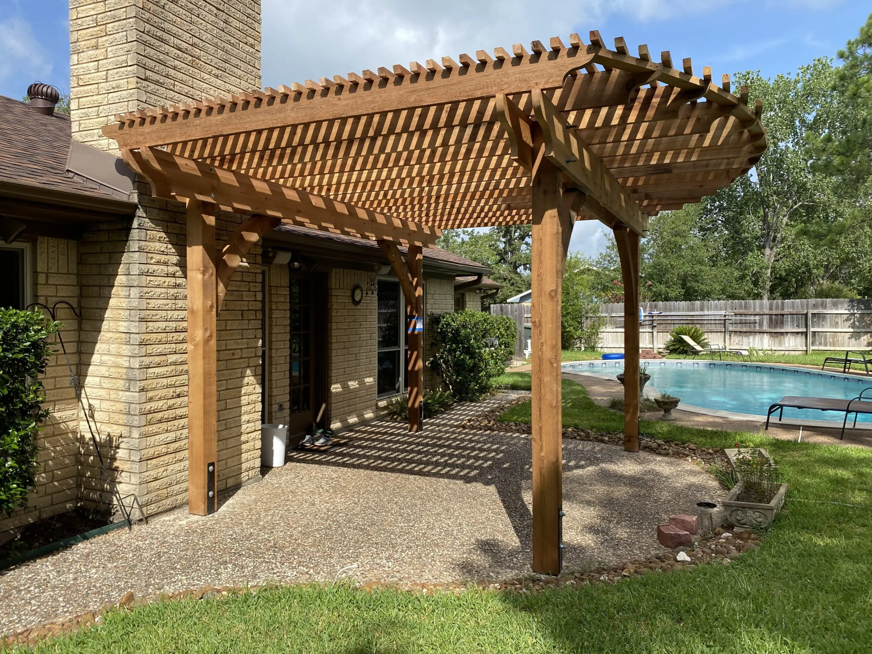 Wooden pergola with a slatted roof casting shadows over a patio area.