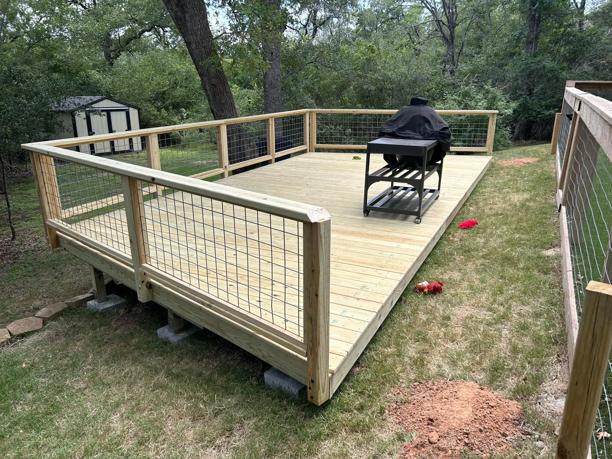 A wooden wheelchair-accessible ramp with railing in a backyard.