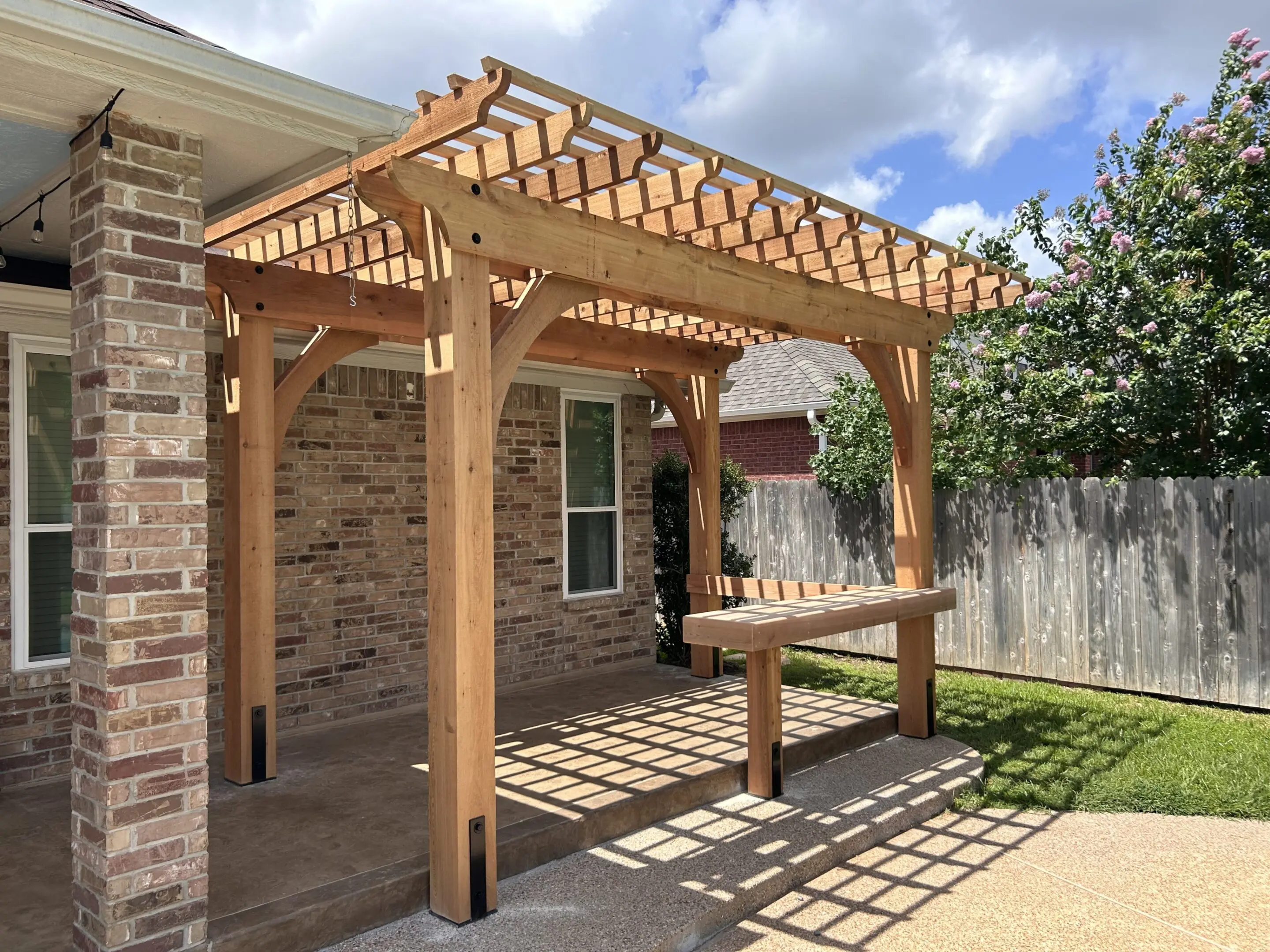 Wooden pergola with bench in sunny backyard patio.