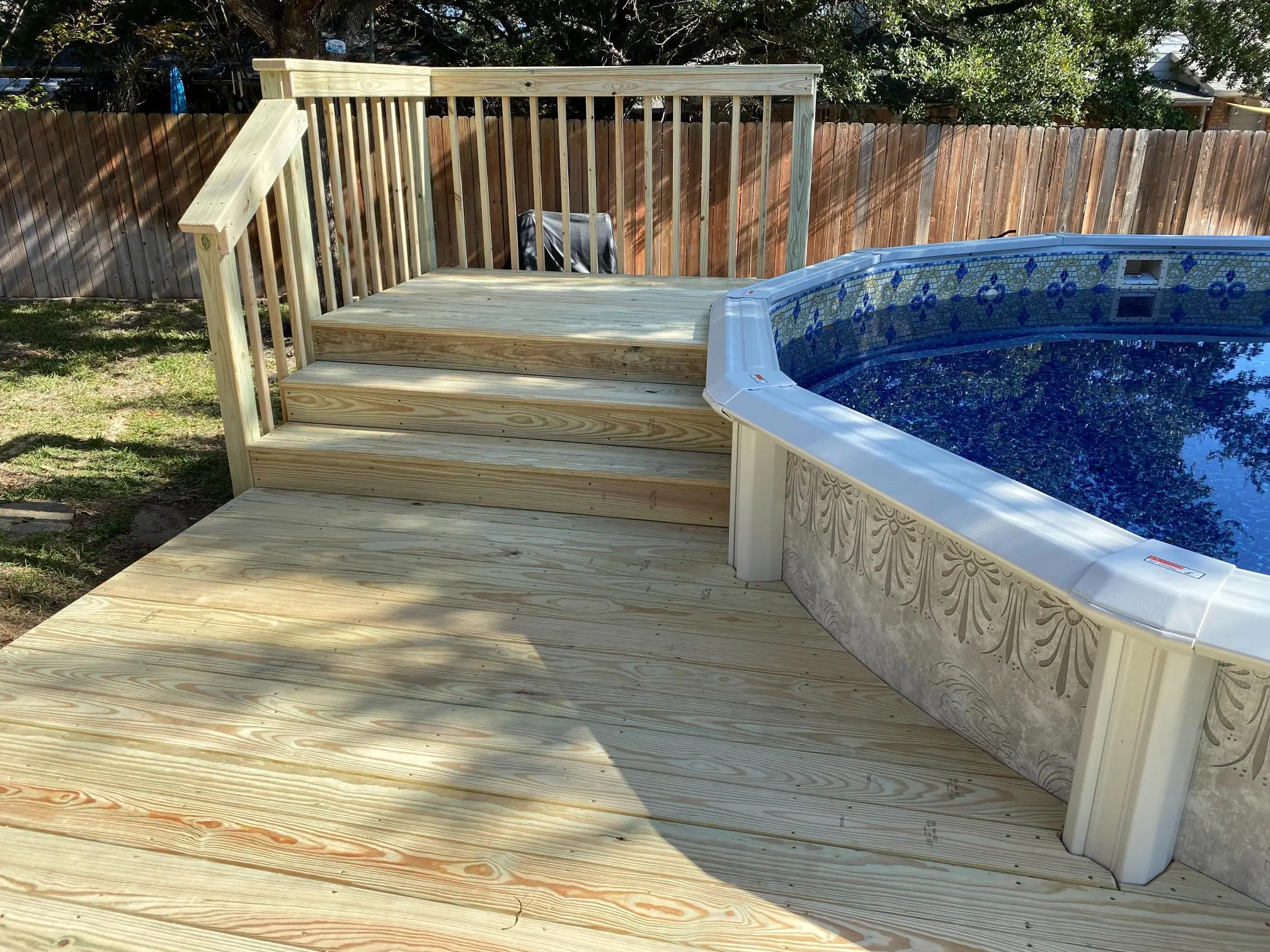 Wooden deck with stairs leading to a round above-ground pool in a backyard.