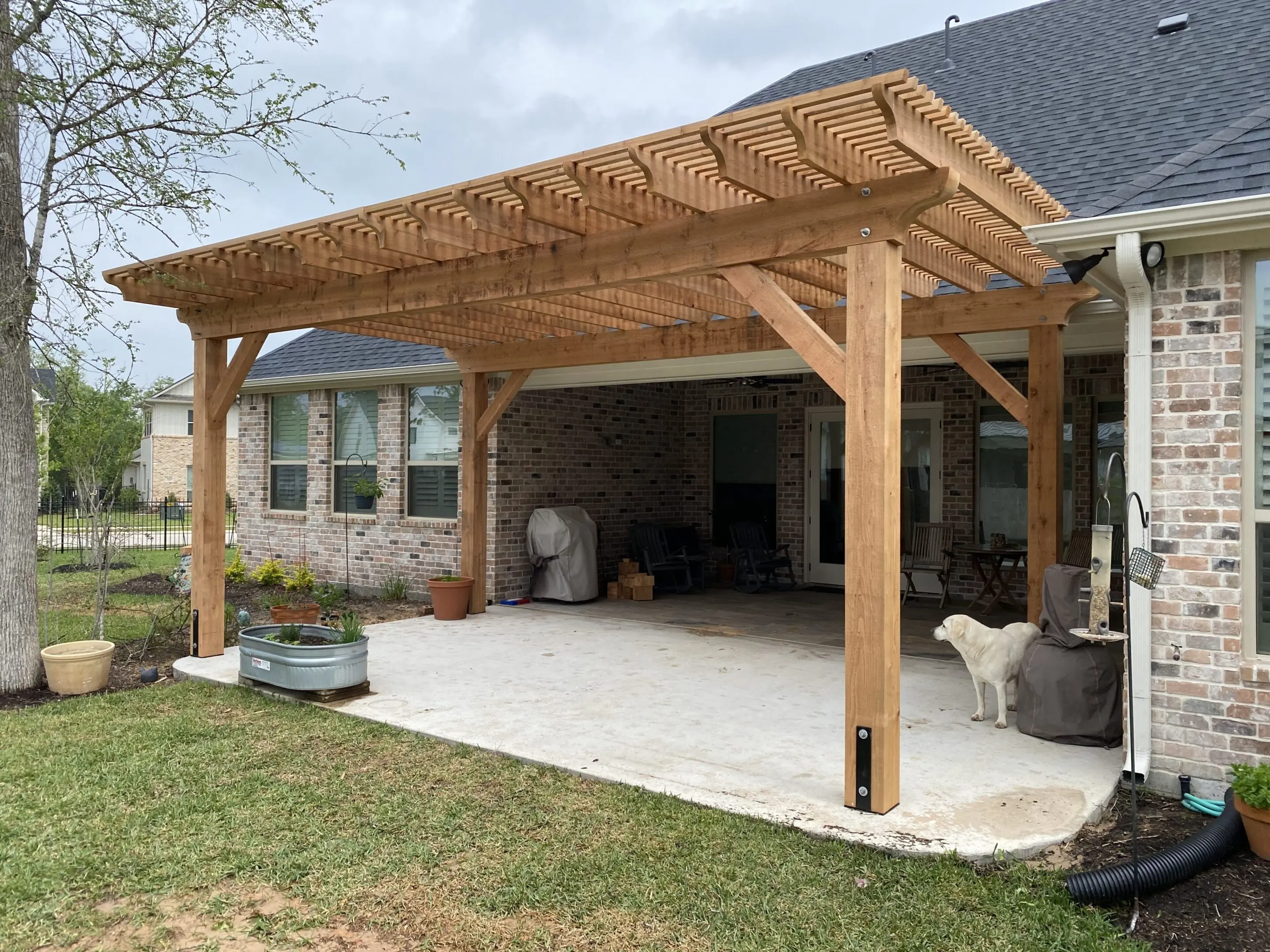 A wooden pergola with a woven cover over a spacious patio.