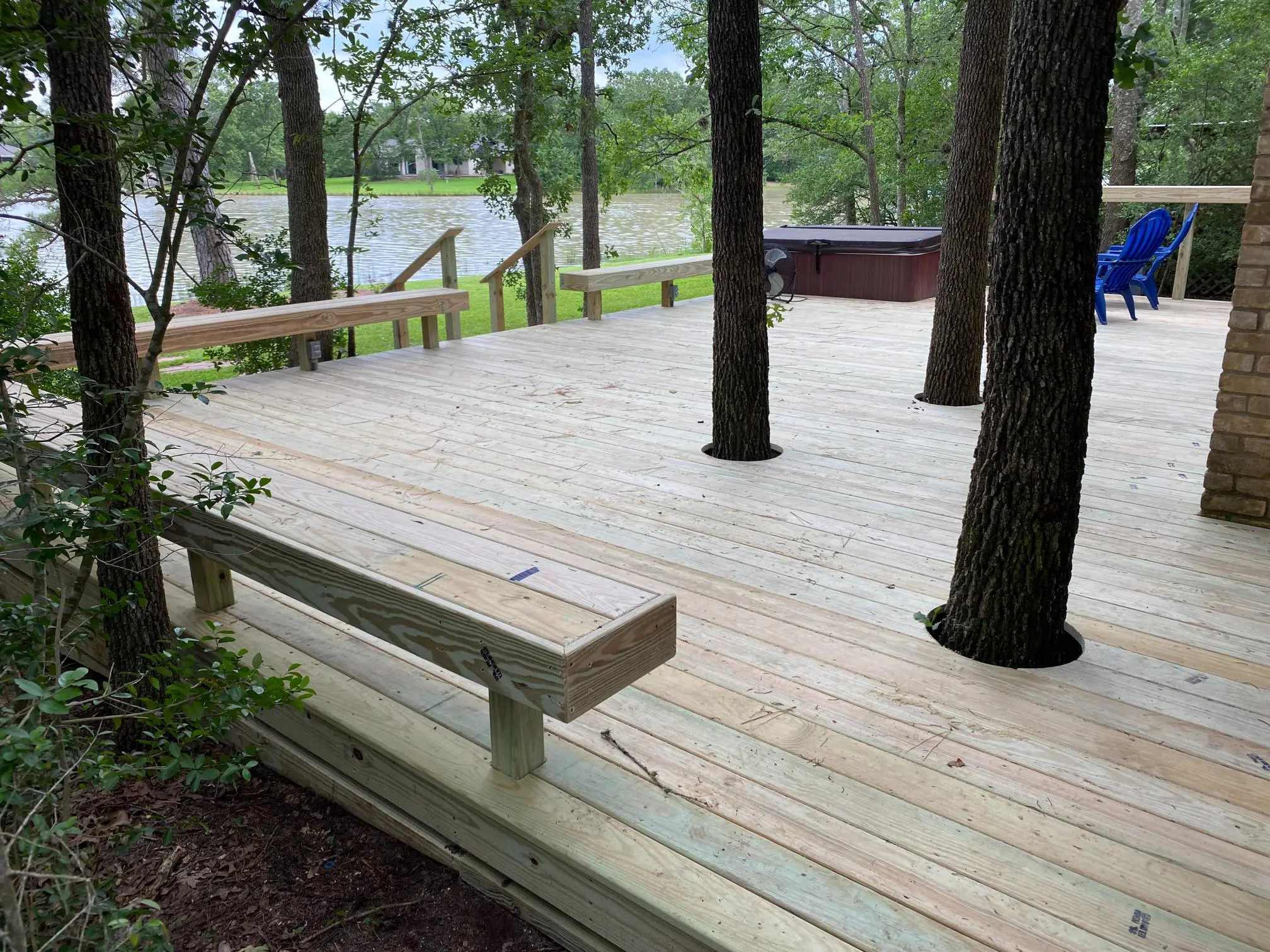 Wooden deck built around trees with a lake view.