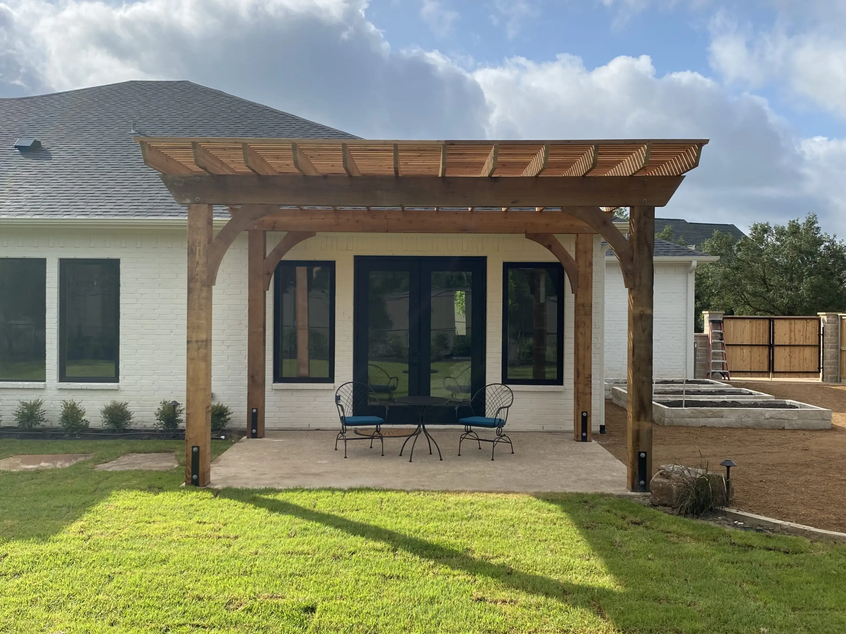 Modern patio with wooden pergola and blue double doors.
