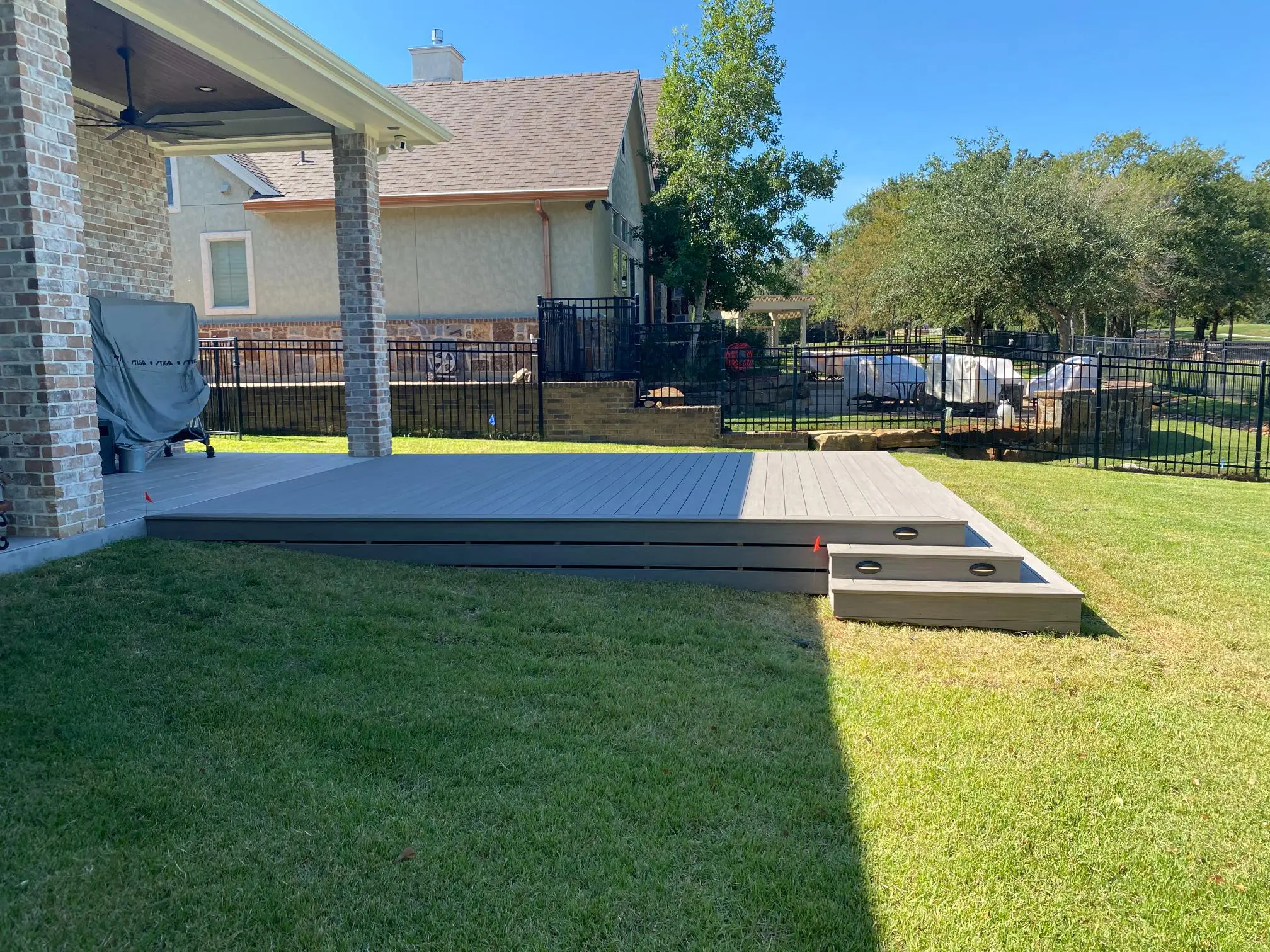 A backyard with a green lawn, concrete patio, and steps.