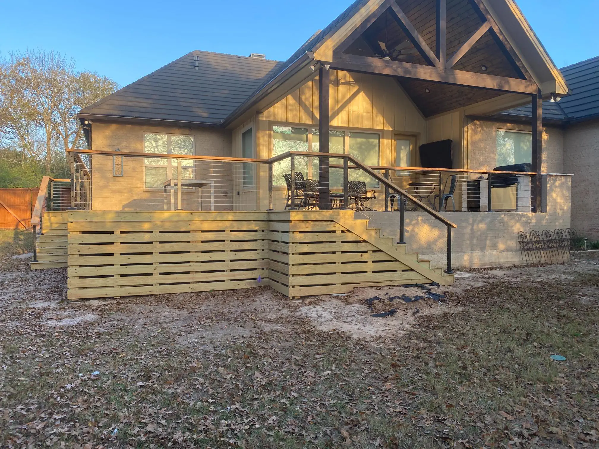 New wooden deck and railing in front of a house under construction.