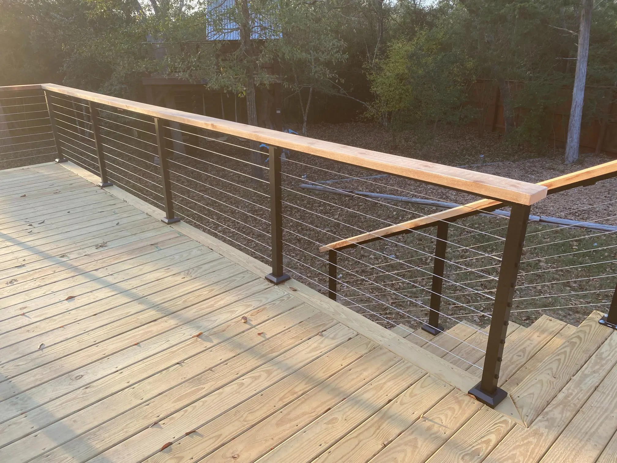 Wooden deck with black metal railings under soft evening light.