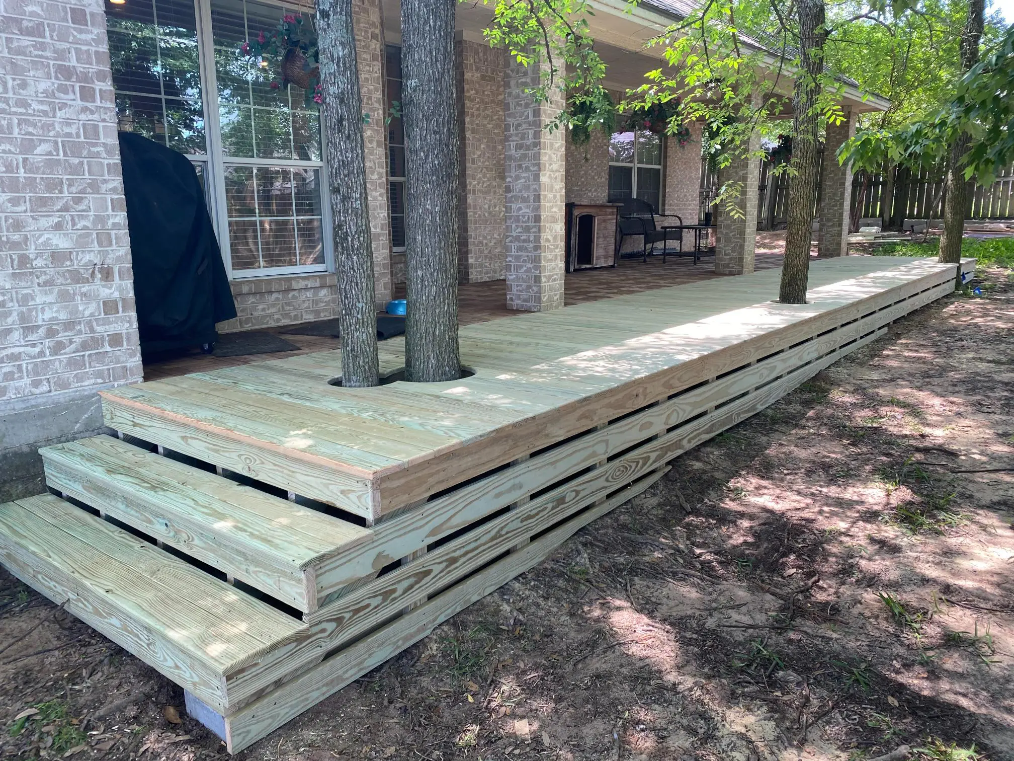 Stack of wooden planks neatly arranged outdoors beside a building.